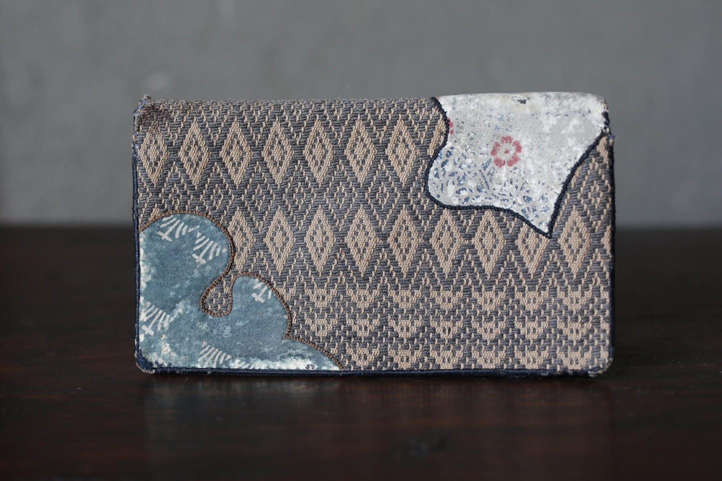 A wallet with a diamond pattern design sits on a dark surface.