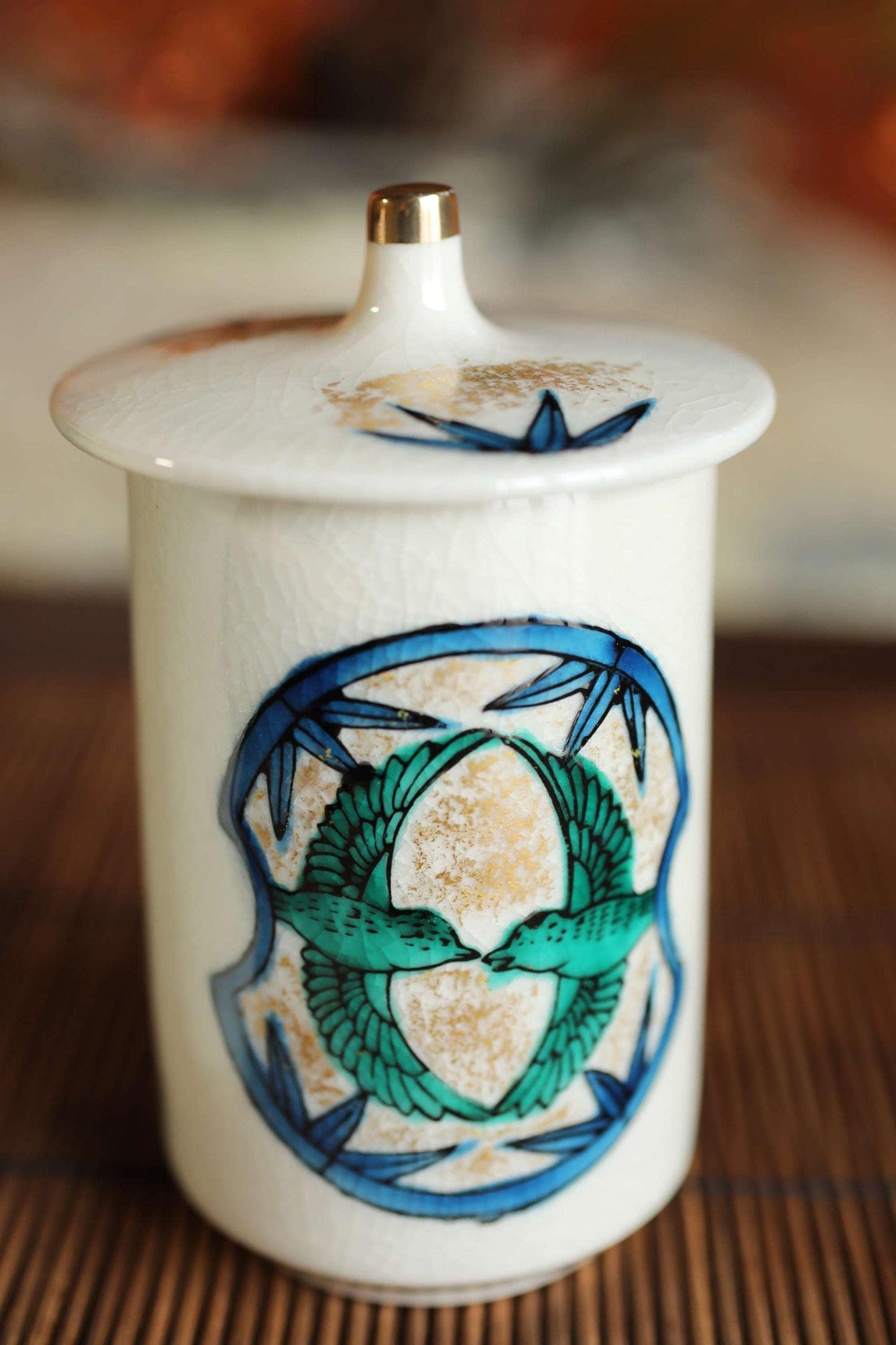 A white ceramic jar with a decorative blue and green design featuring two stylized birds.