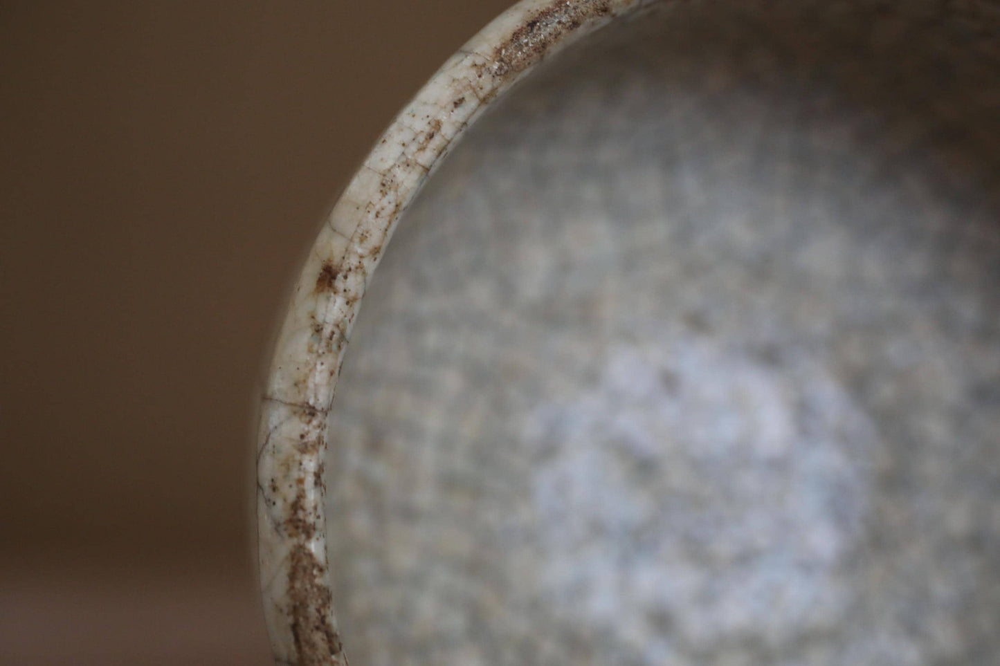 A close-up view of a dirty, textured surface with a white, curved edge.