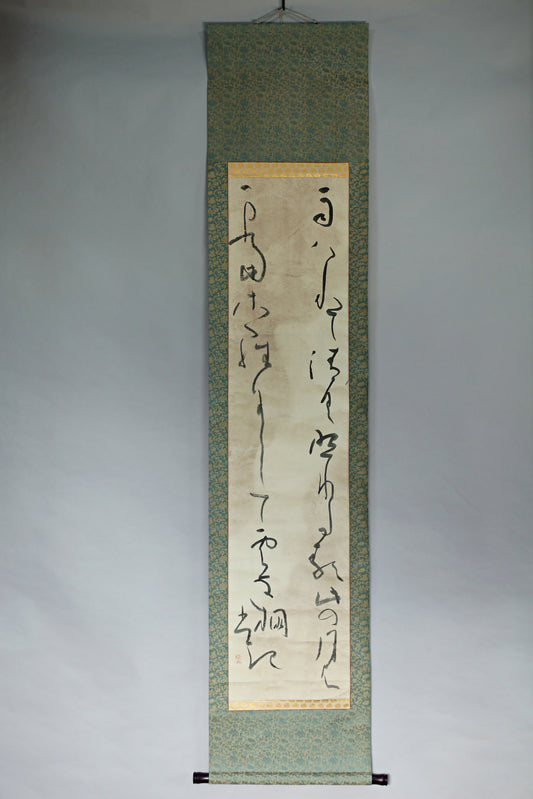 a vertical scroll with Chinese characters on it, hanging on a wall.