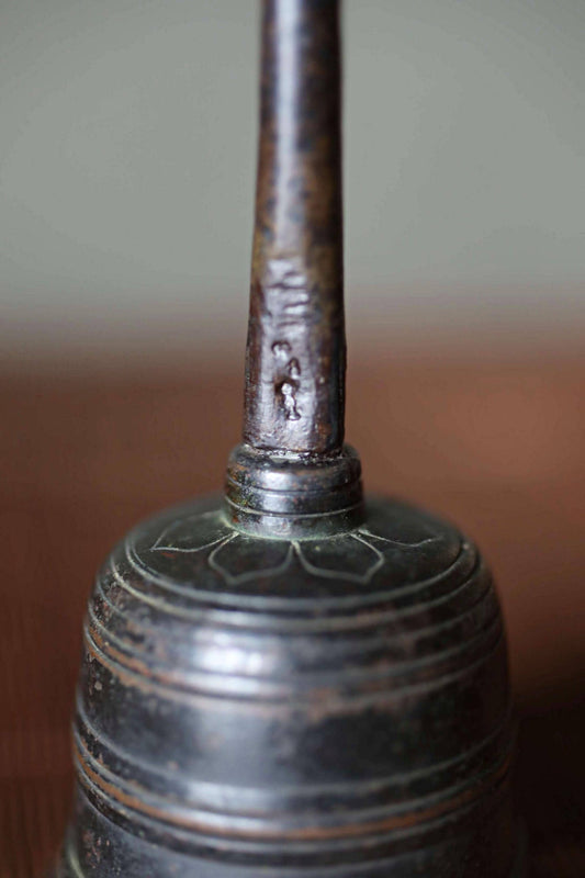 A close-up image of a metal bell with a textured surface and a small hole on the top.