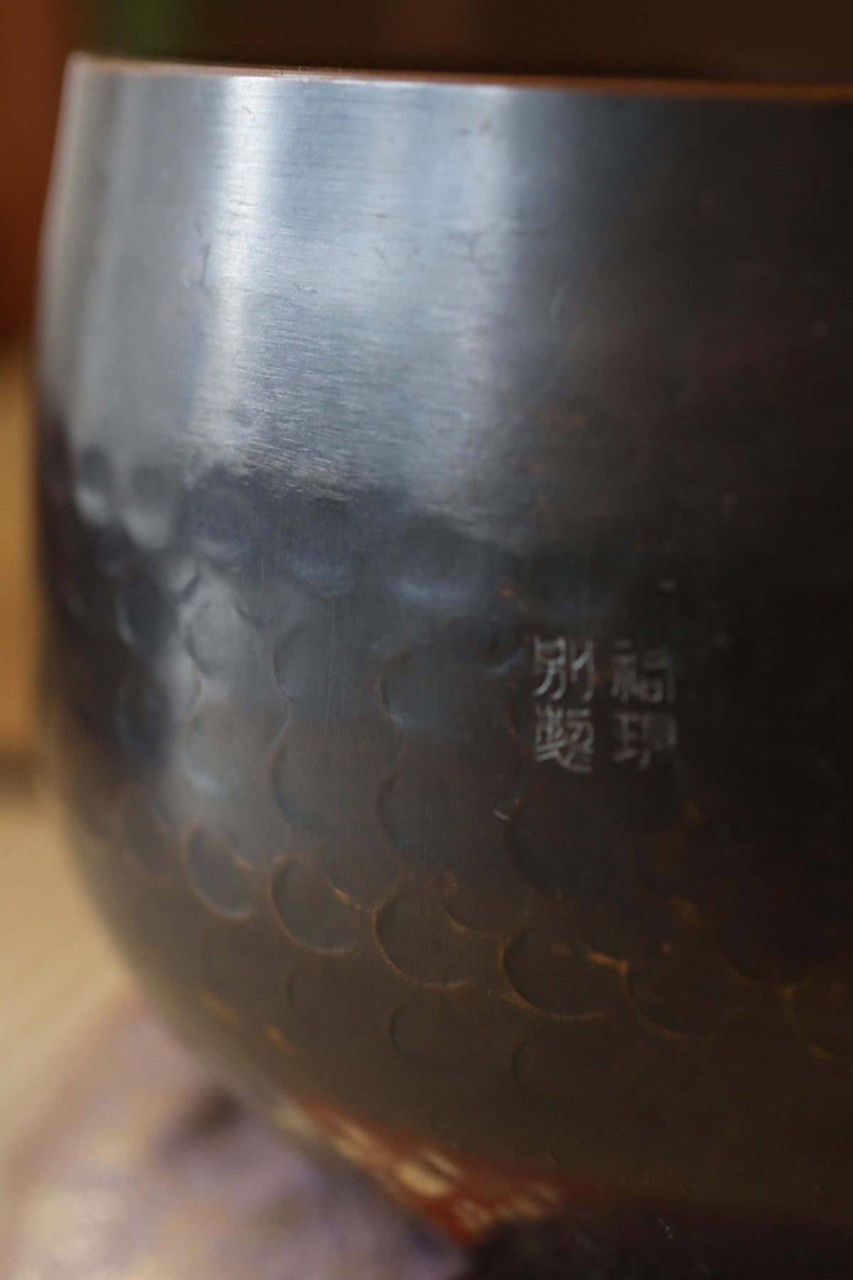 A close-up image of a dark, textured bowl or container with a pattern of circles or ovals on its surface.