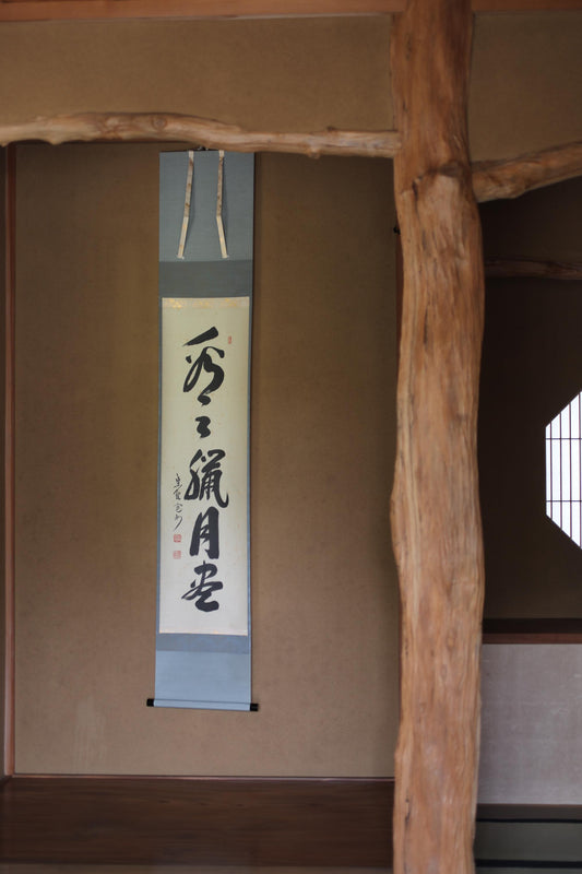a wooden beam with a vertical scroll hanging on the wall, displaying Japanese characters.