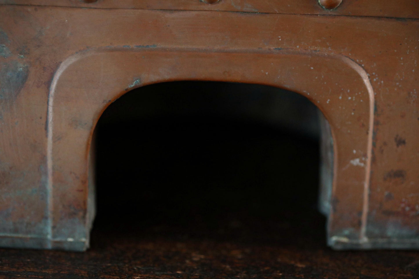 a close-up view of a dark, arched opening or doorway, with a reddish-brown hue.