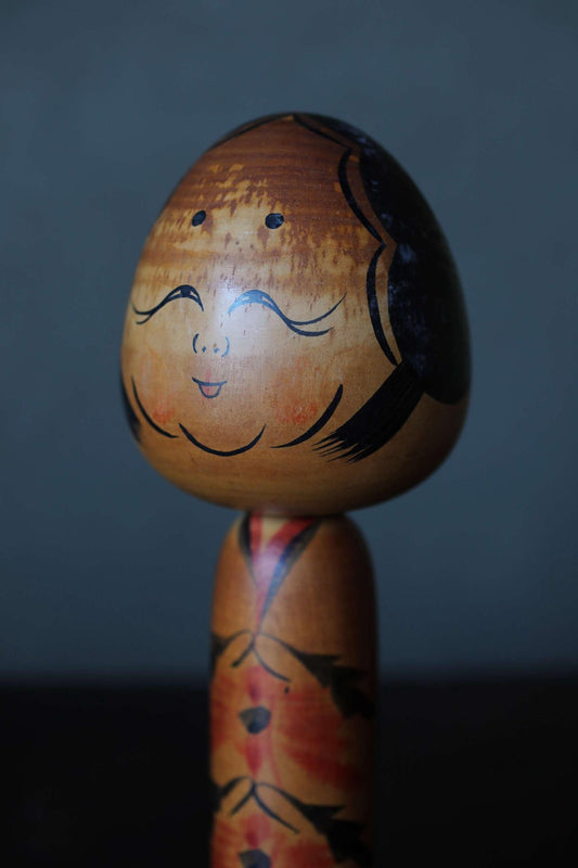 A wooden doll with a face painted on it, standing on a wooden base.