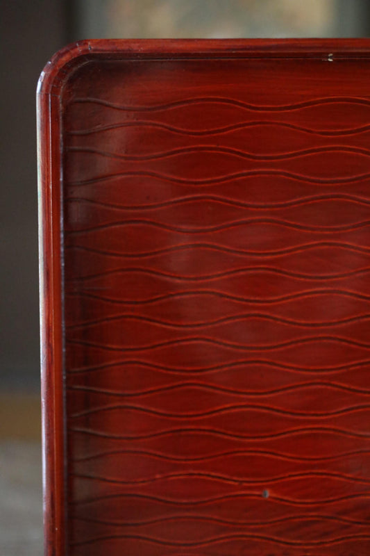 a close-up view of a wooden surface with a distinctive wavy pattern, likely made of a dark-colored wood.