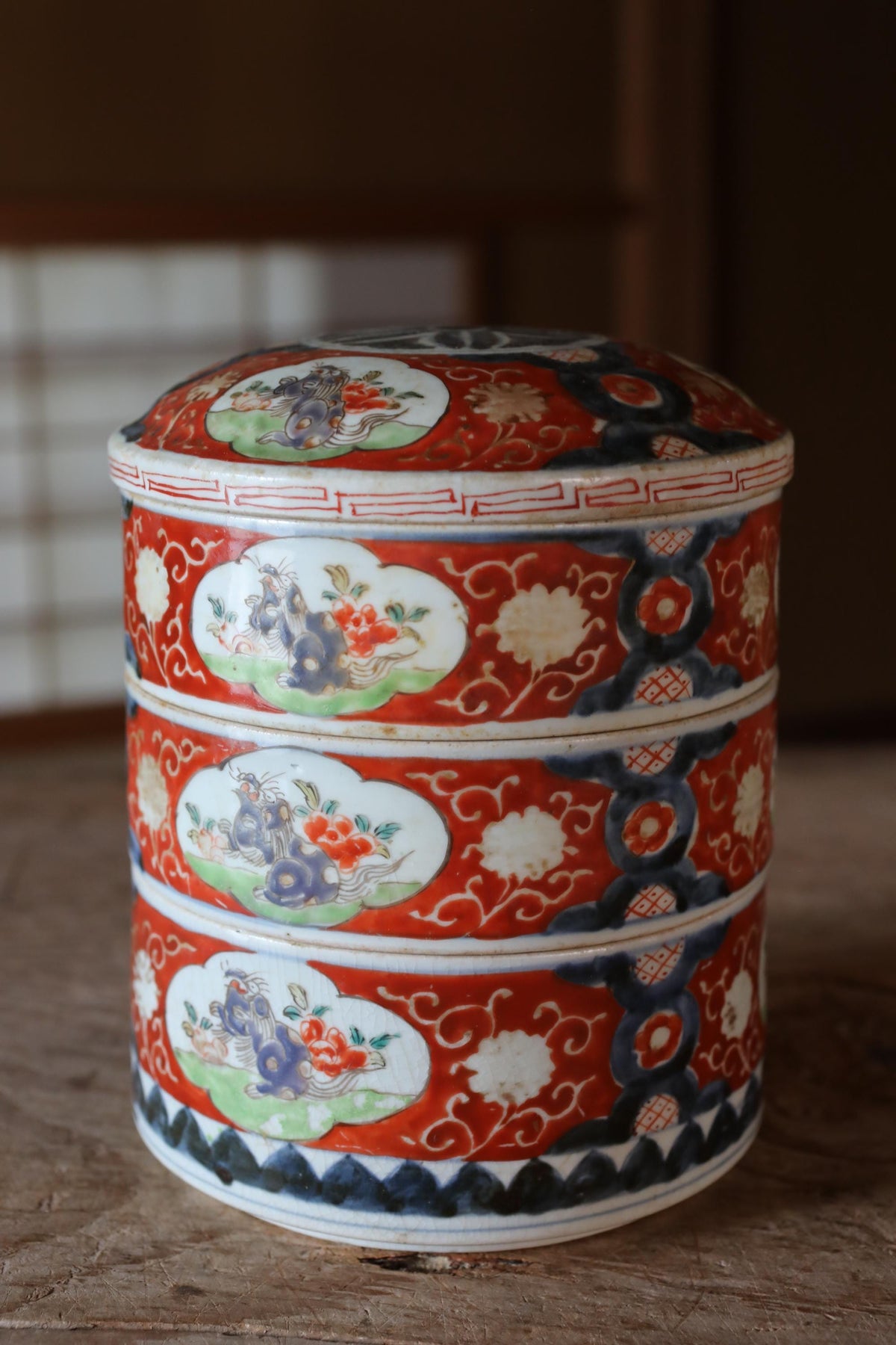 A decorative ceramic container with a red and white color scheme, featuring intricate floral and animal designs.