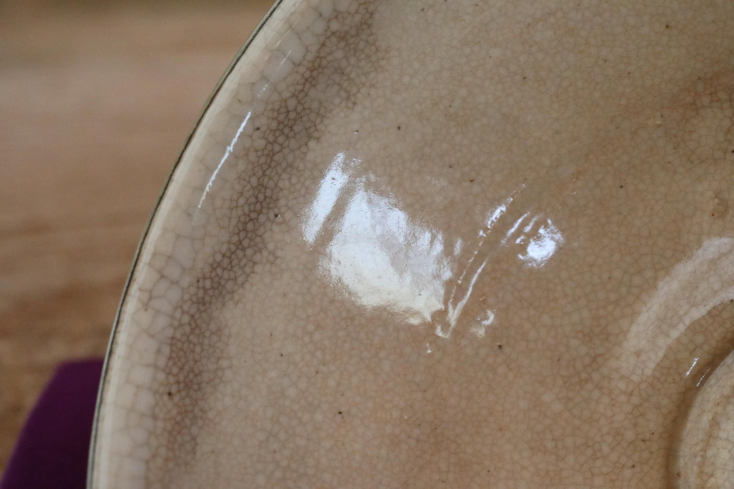 A close-up view of a textured ceramic bowl or plate, with a shiny, reflective surface.