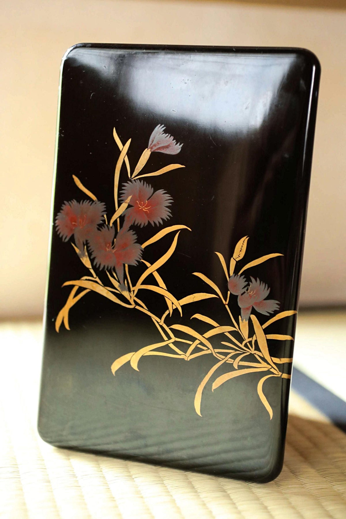 a black rectangular object with a floral design on it, placed on a surface.