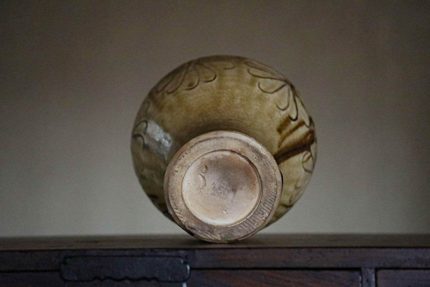 A ceramic vase with a floral design sits on a wooden surface.