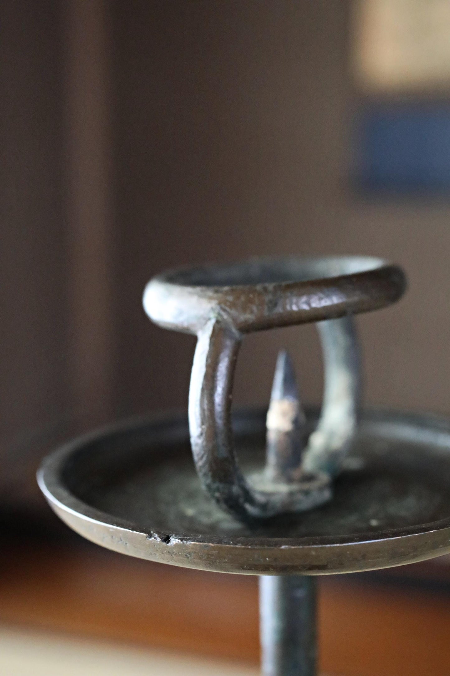 A close-up view of an antique-looking metal candlestick holder with a circular base and a handle.