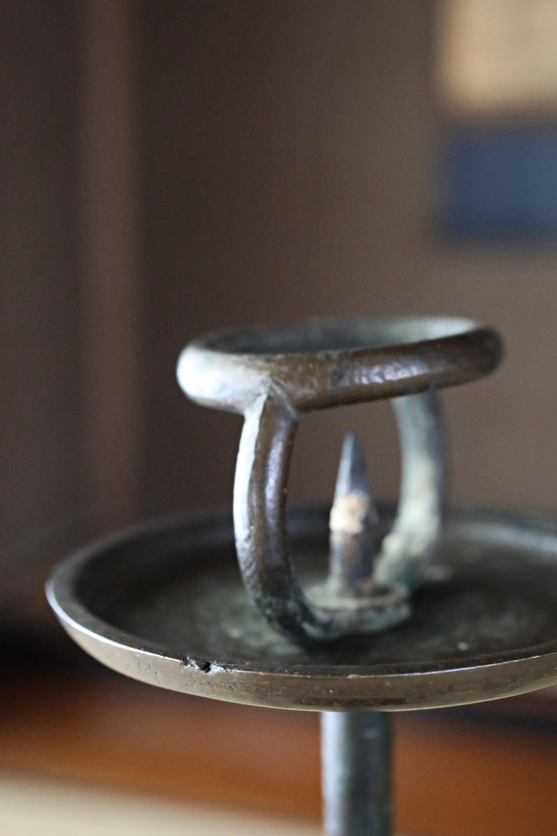 A close-up view of an antique-looking metal candlestick holder with a circular base and a handle.