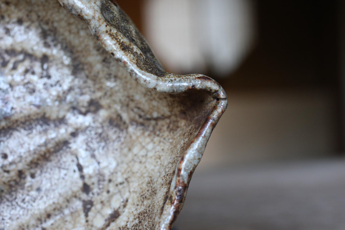 A close-up view of a textured, weathered ceramic object, possibly a piece of pottery or a decorative item.