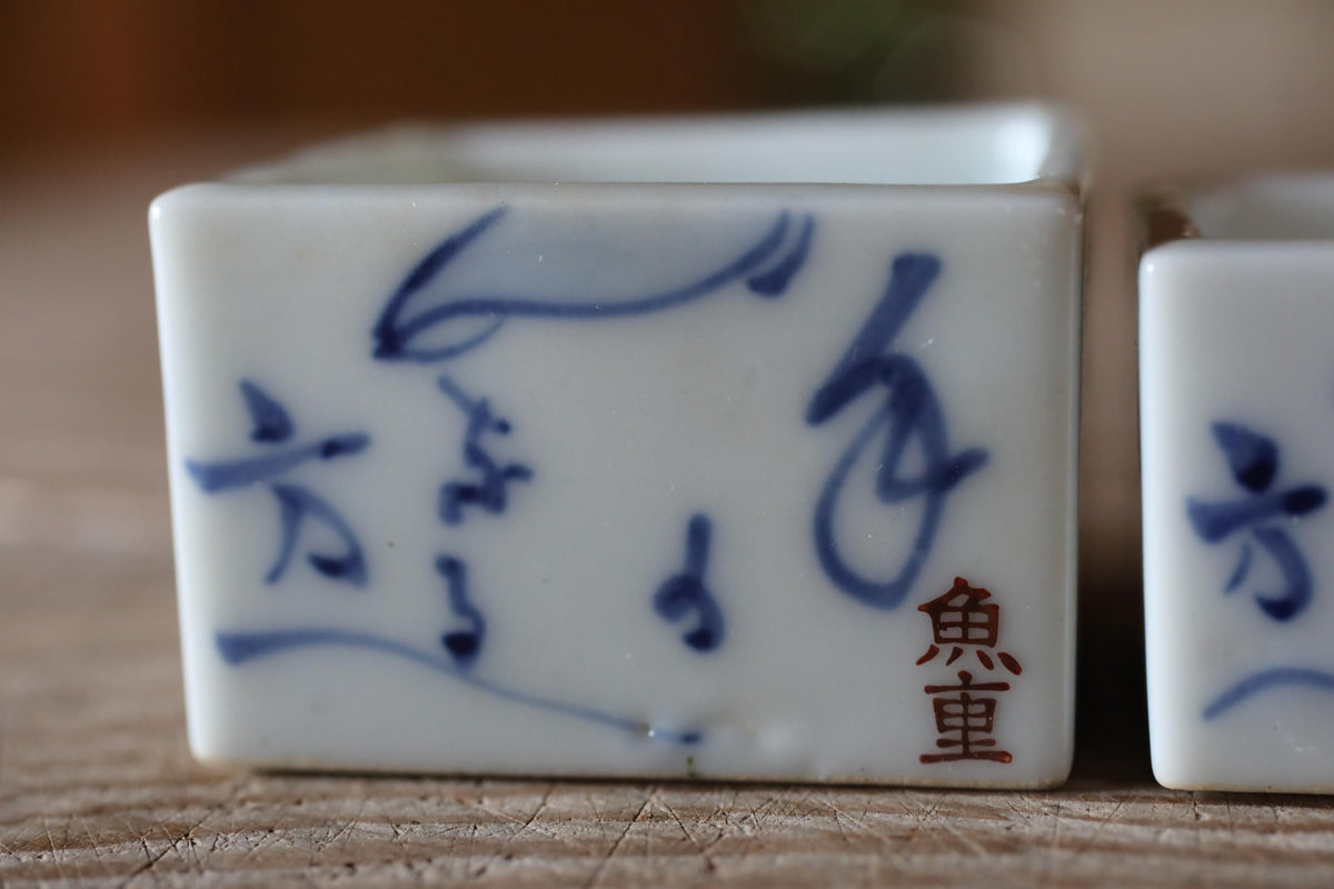 A close-up image of a white ceramic container with blue Chinese characters and a red Chinese character on it.
