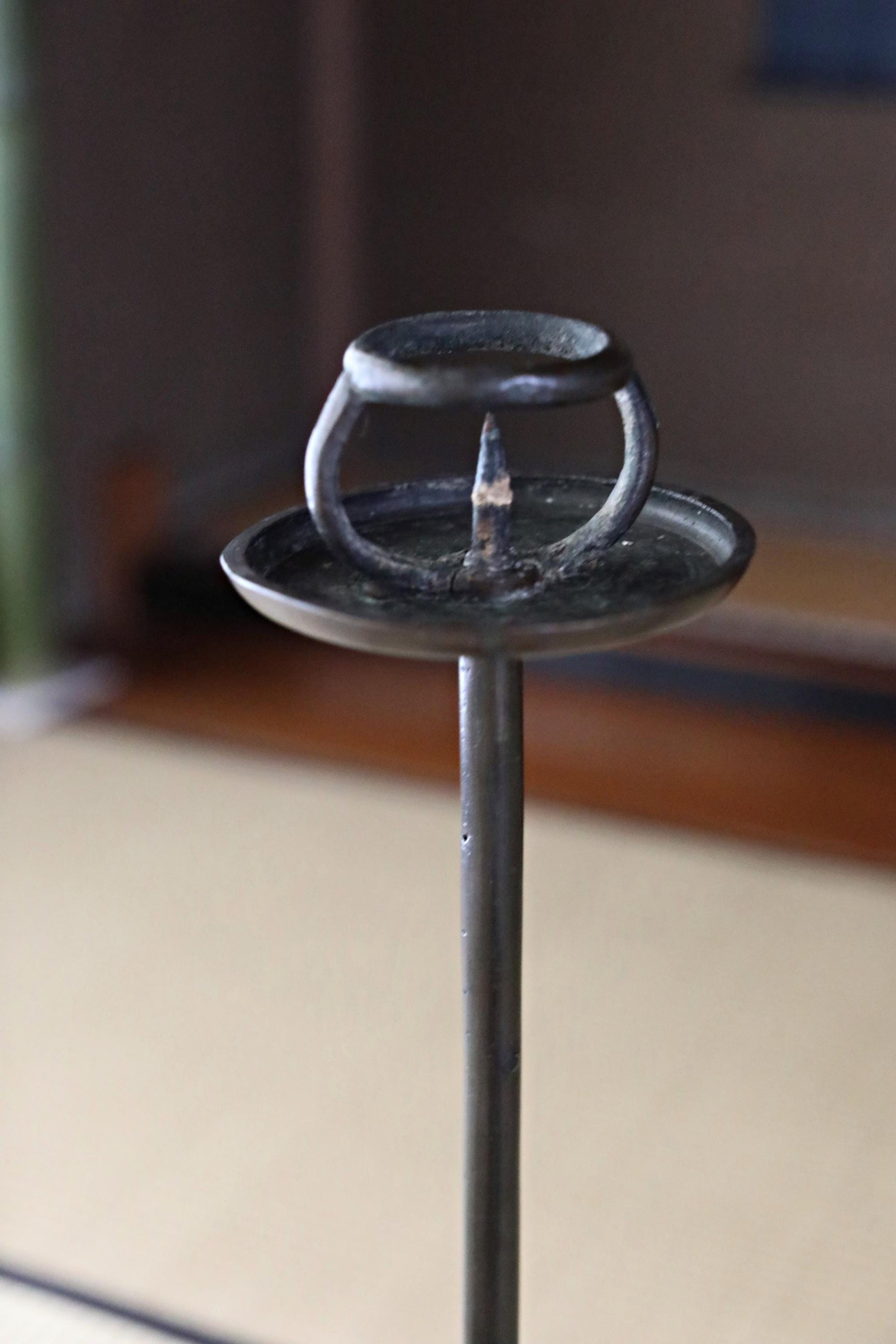A close-up view of a metal candle holder with a small candle in it, placed on a wooden surface.