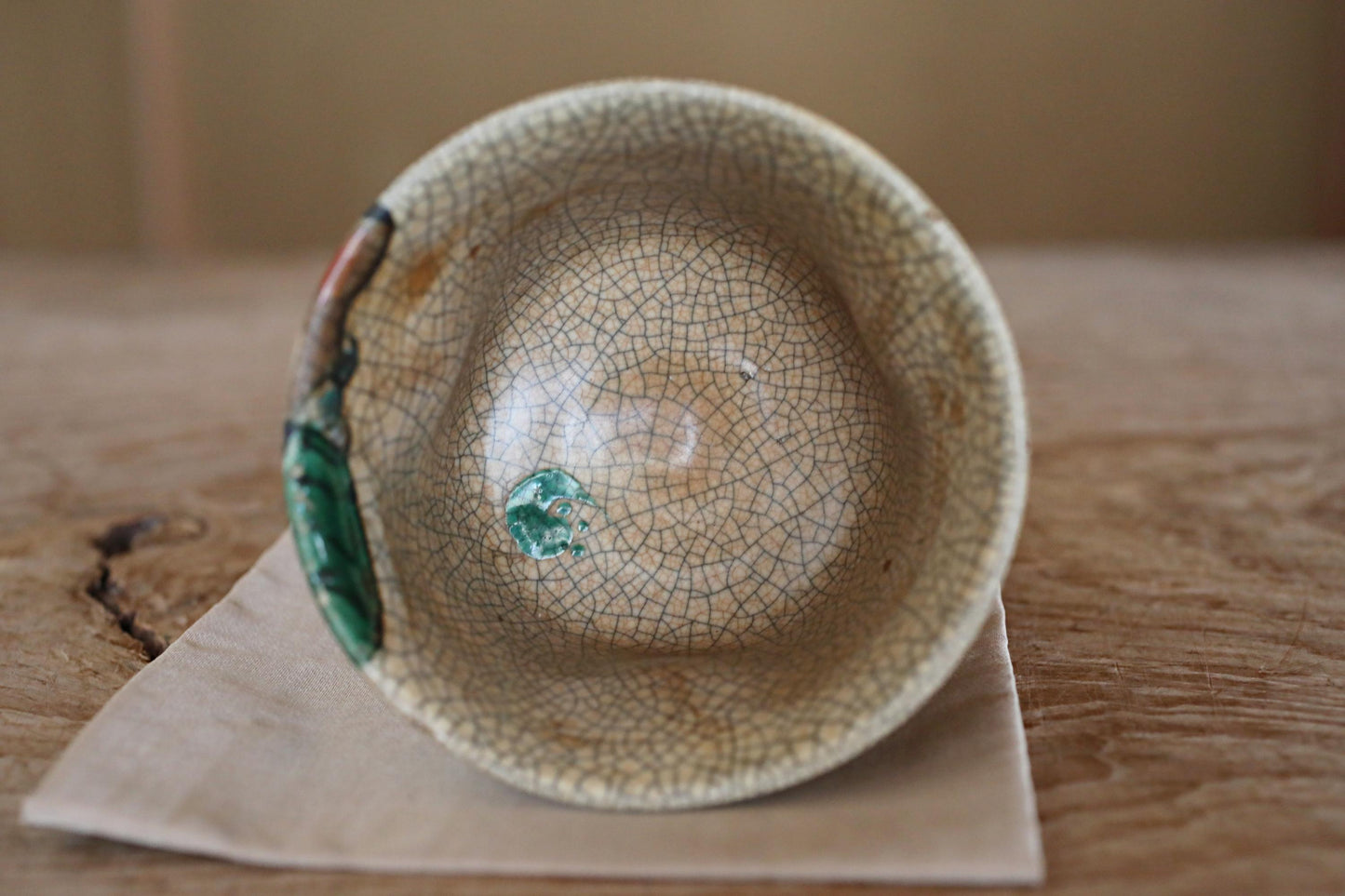 A ceramic bowl with a green and white patterned design sits on a wooden surface.