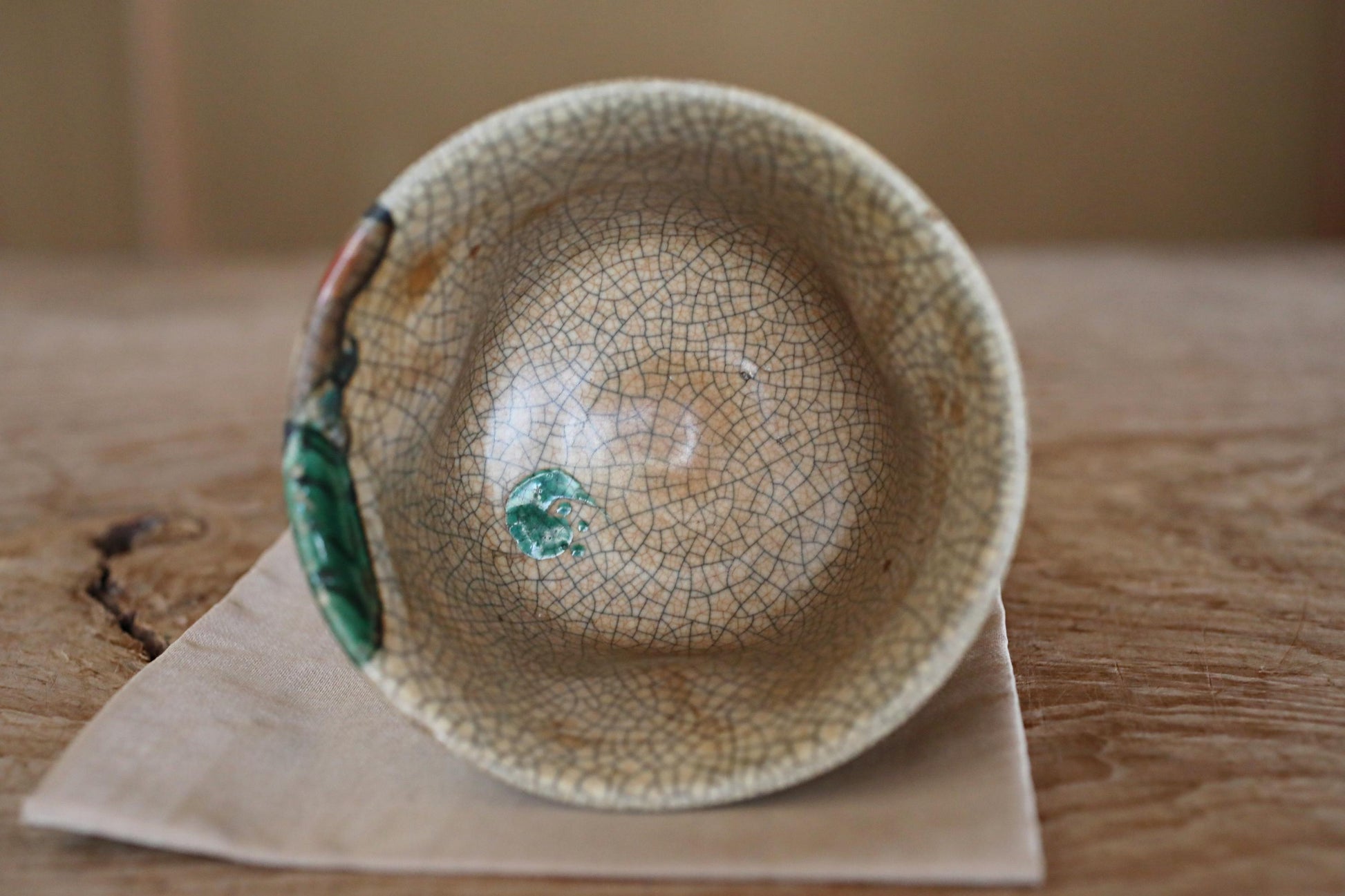 A ceramic bowl with a green and white patterned design sits on a wooden surface.