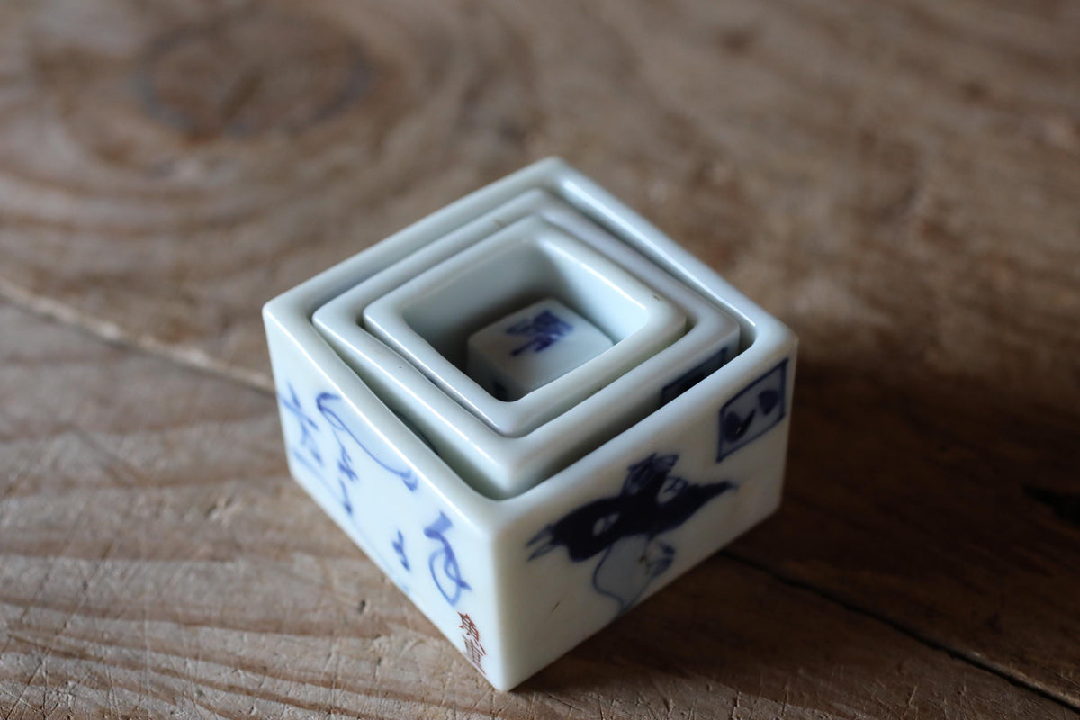 A white ceramic container with blue designs and text, sitting on a wooden surface.