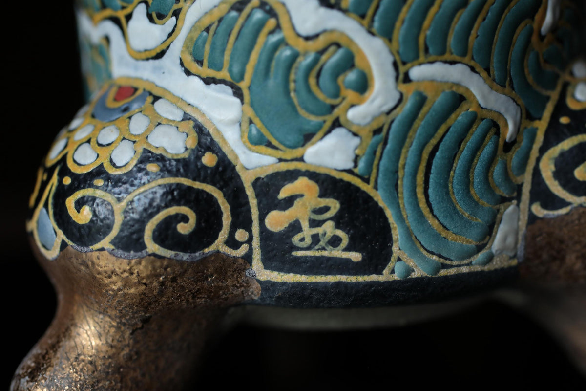 A close-up image of a decorative ceramic piece with intricate patterns and designs in various colors, including blue, green, and gold.