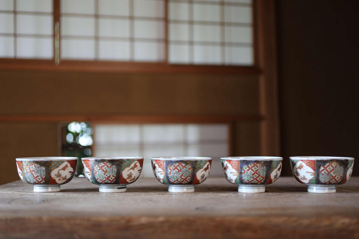 A row of five colorful ceramic bowls with intricate designs, arranged on a wooden surface.