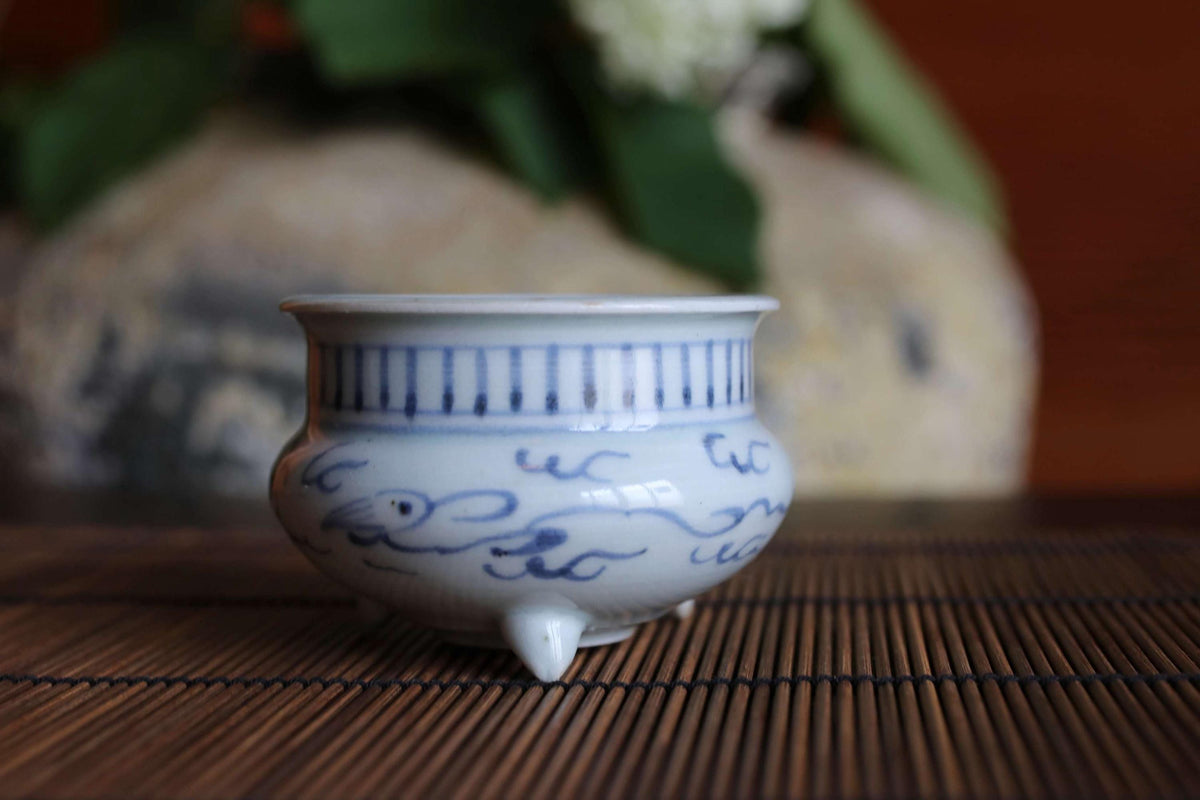 A small blue and white ceramic bowl with a decorative design sits on a bamboo mat.