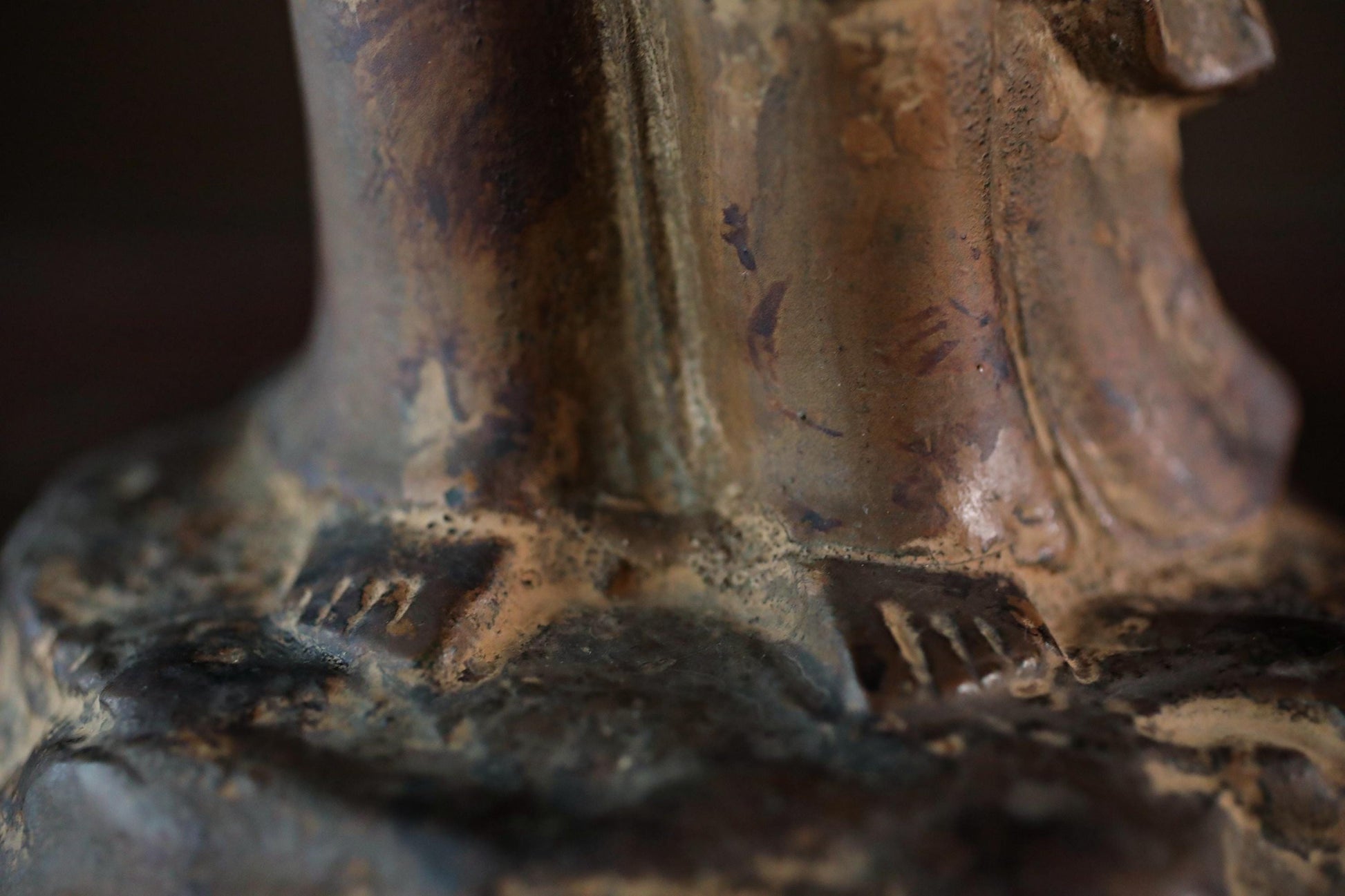 A close-up view of a weathered, rusted metal sculpture with a textured surface.