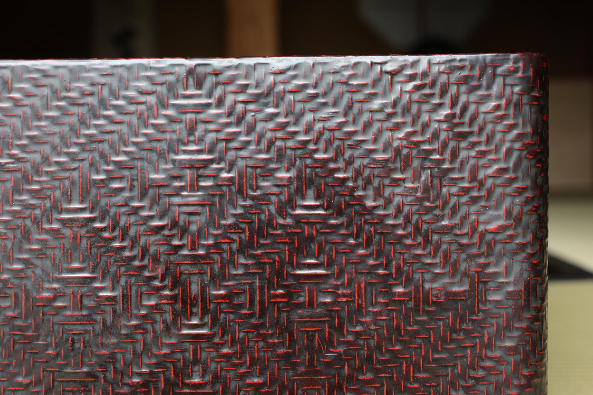 a close-up view of a textured surface with a red and black pattern, possibly a woven or embossed material.