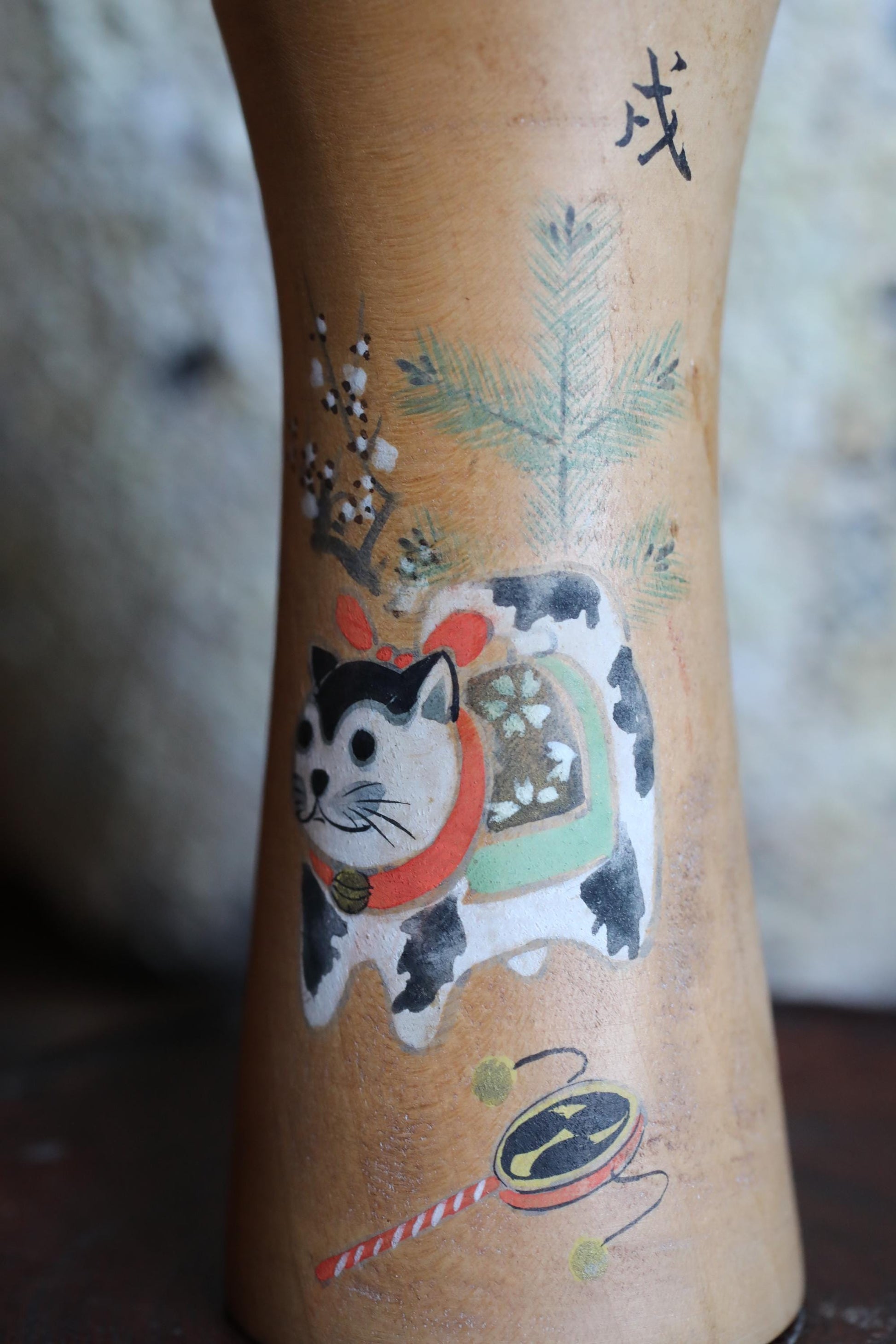a detailed drawing of a cat on a vase, with various decorative elements surrounding it, including a pine tree and other floral designs.