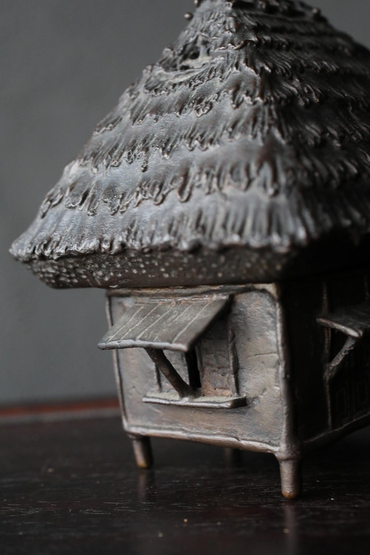 A close-up view of a small, intricately designed metal sculpture resembling a house or a similar structure.