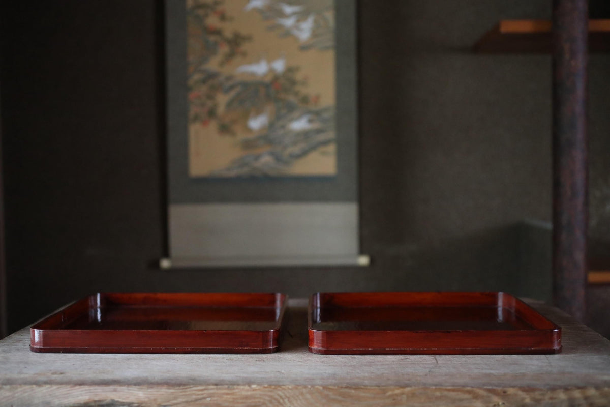 two wooden trays placed on a wooden surface, with a painting hanging on the wall in the background.