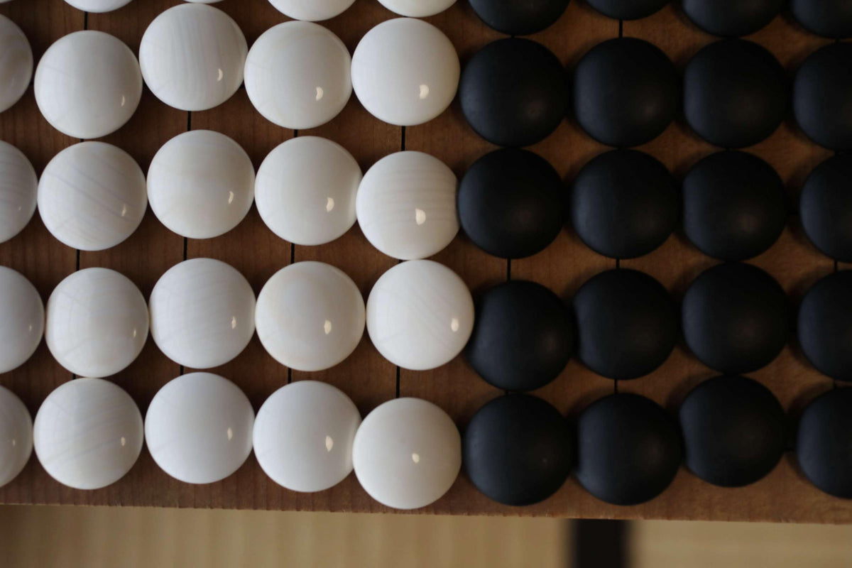 a close-up view of a wooden surface with a pattern of white and black circles arranged in a grid-like pattern.