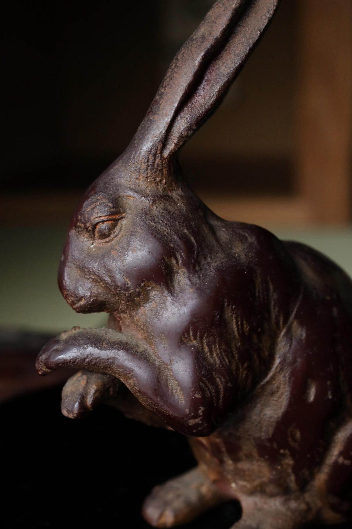 A close-up view of a dark brown, weathered metal rabbit figurine.