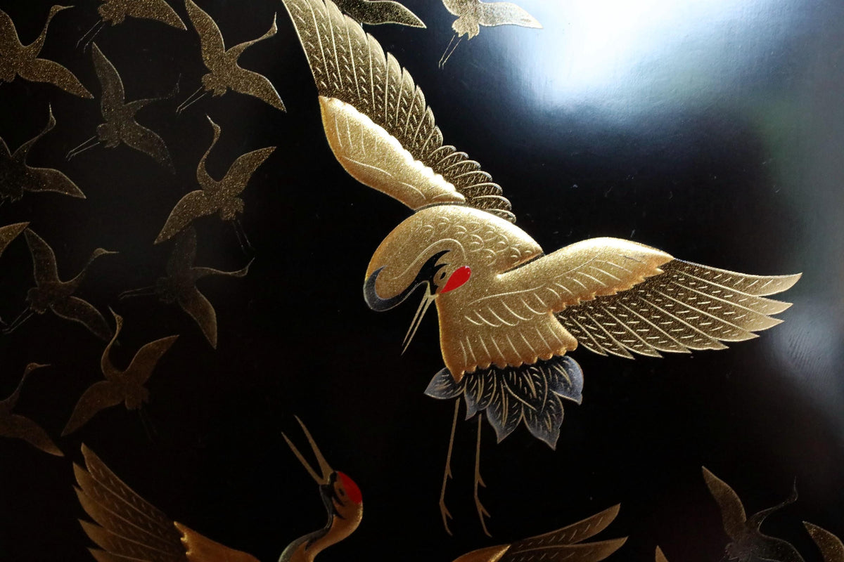 a close-up view of a detailed gold-colored crane sculpture against a dark background.