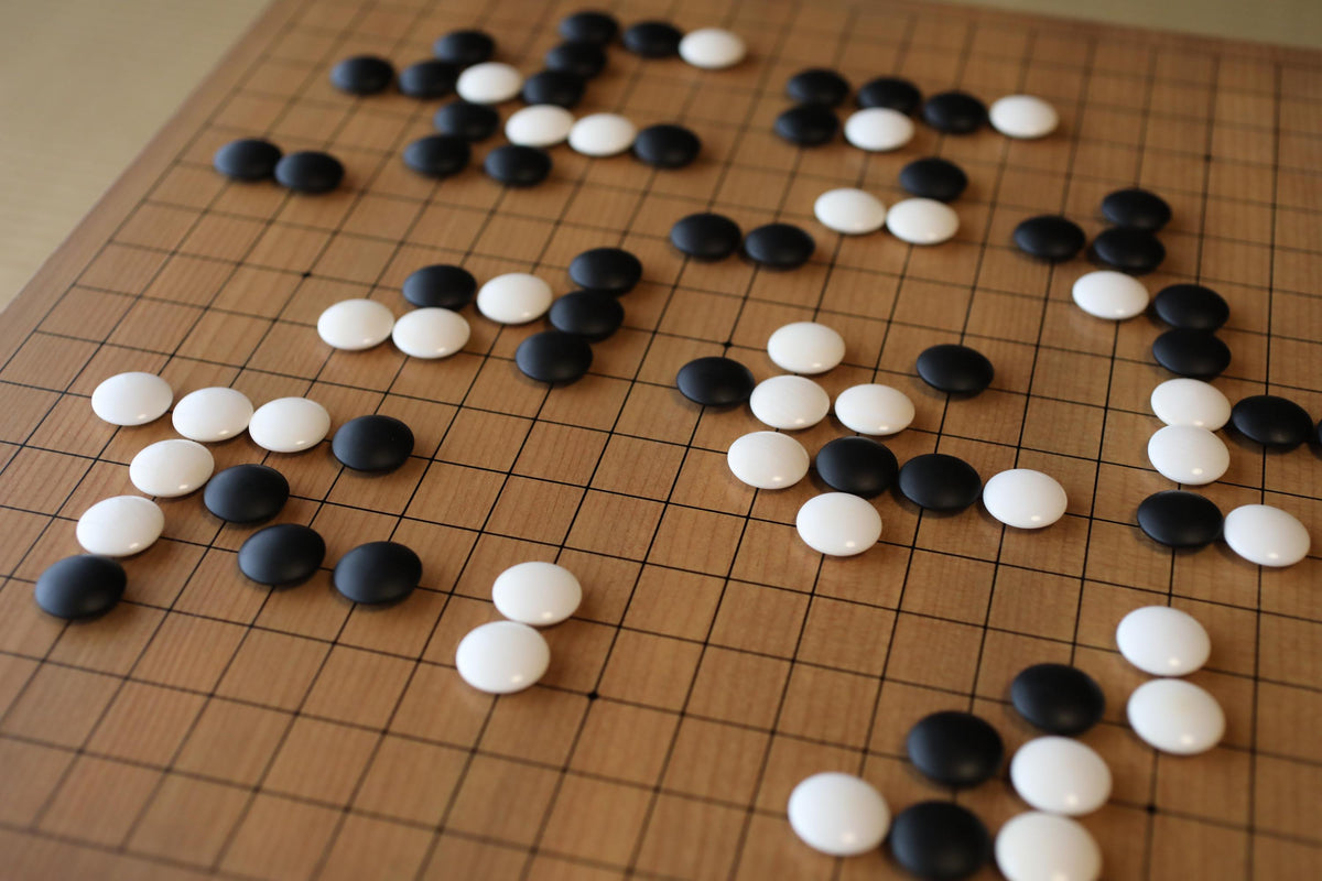 a wooden game board with black and white game pieces scattered across it.