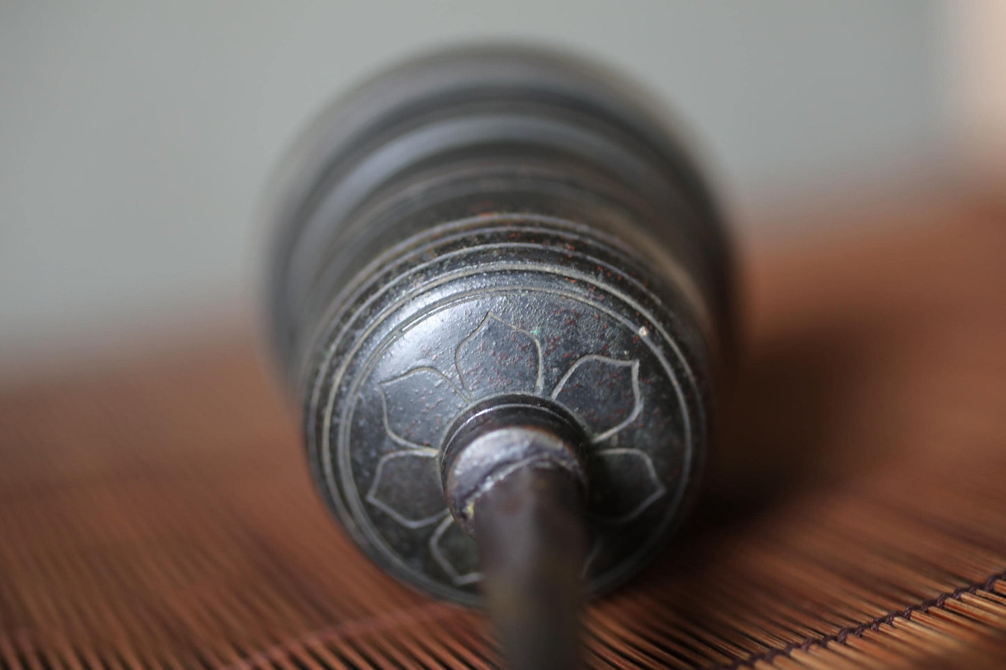 A close-up view of a metal object with a floral design on its surface, resting on a wooden surface.