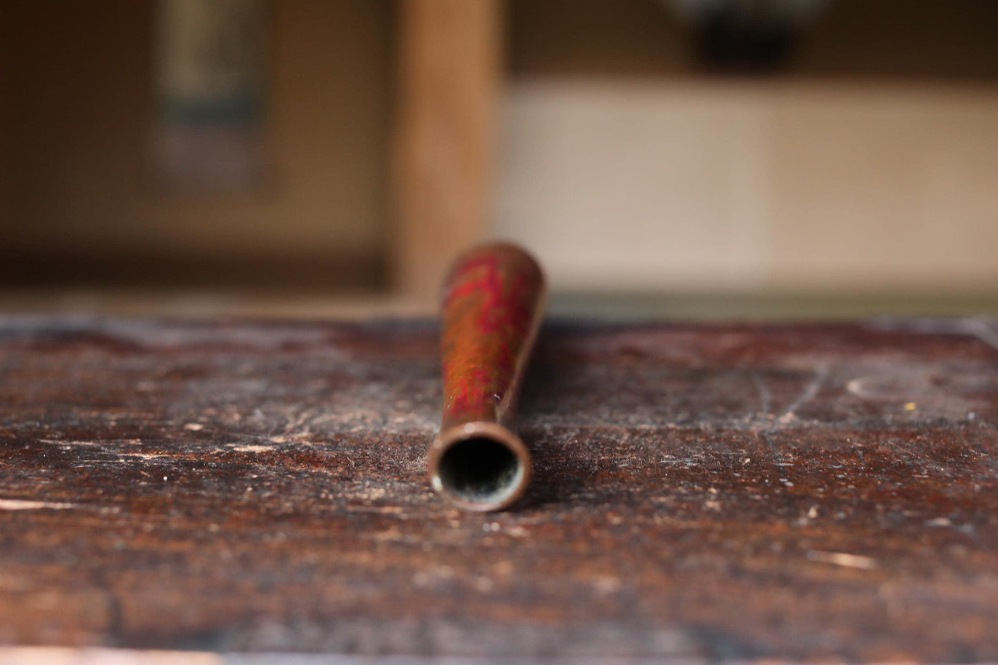 A red and orange baseball bat is lying on a wooden surface.