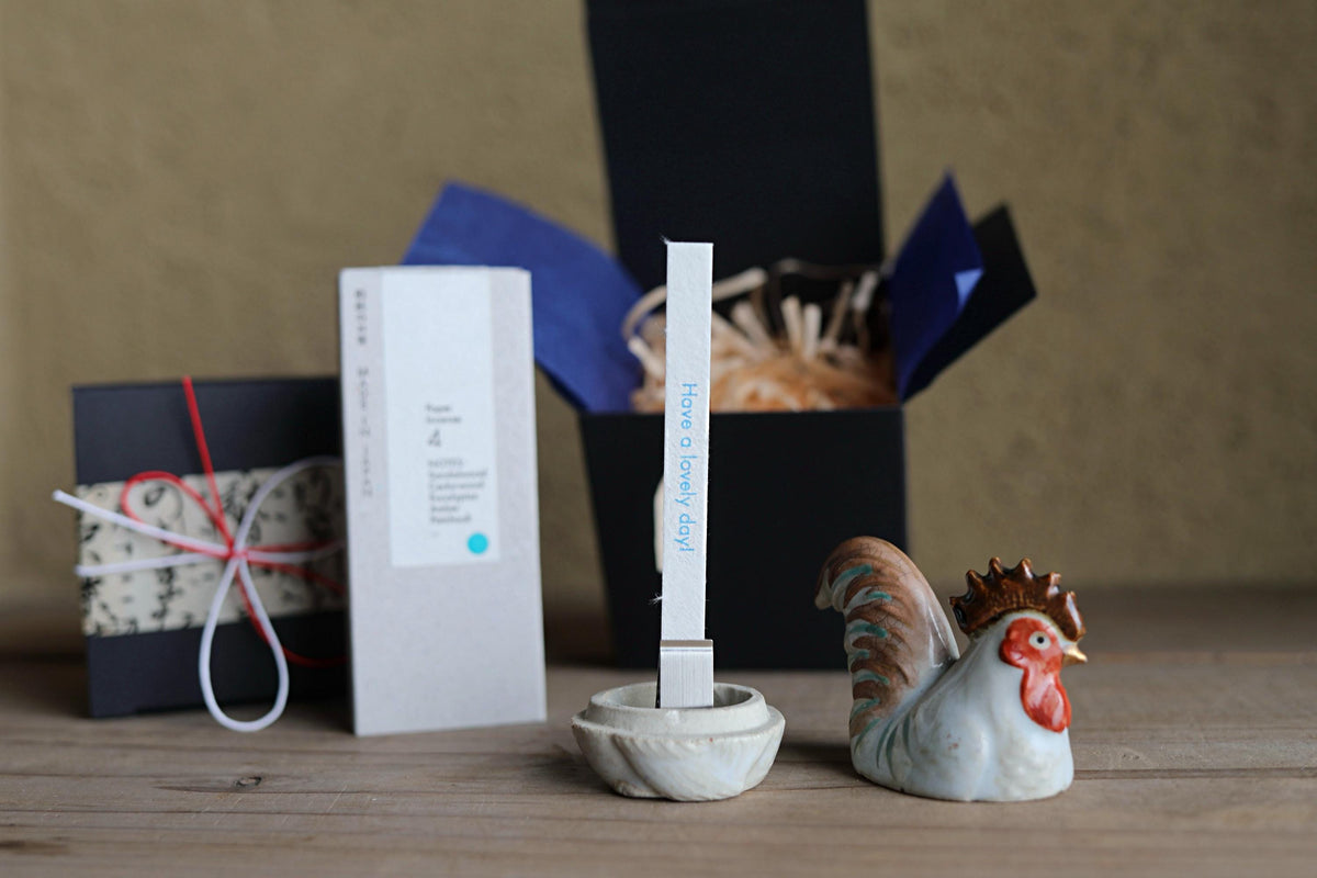 a wooden table with various objects, including a white box, a ceramic rooster figurine, and a small white object with a blue label.