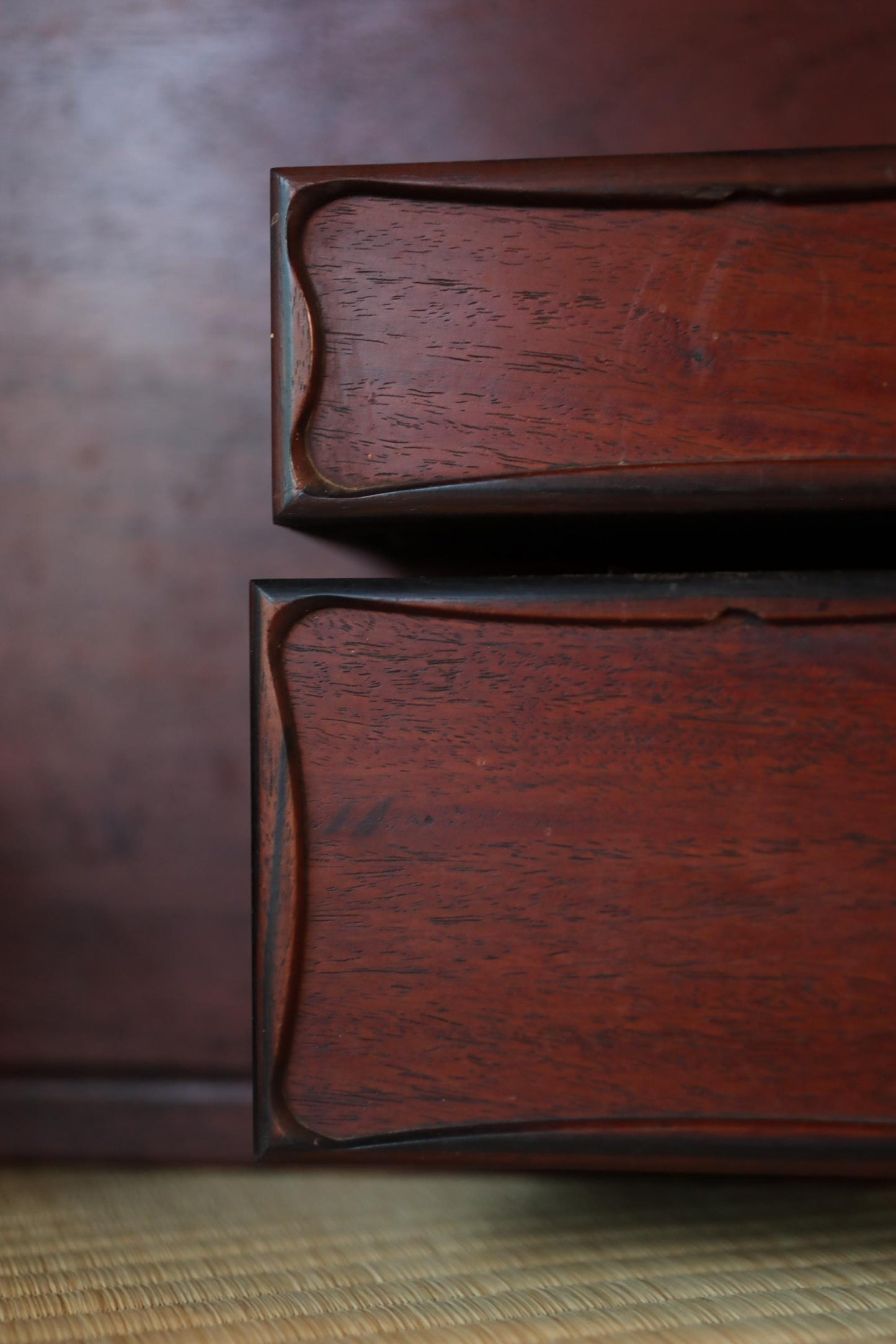 two wooden bookshelves with dark wood and a textured finish, placed against a dark background.