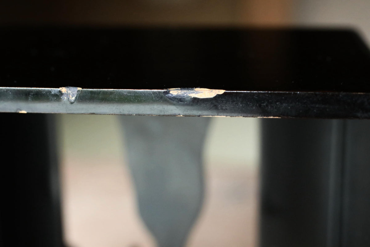 a close-up view of a black surface with a noticeable crack or damage, possibly on a table or shelf.