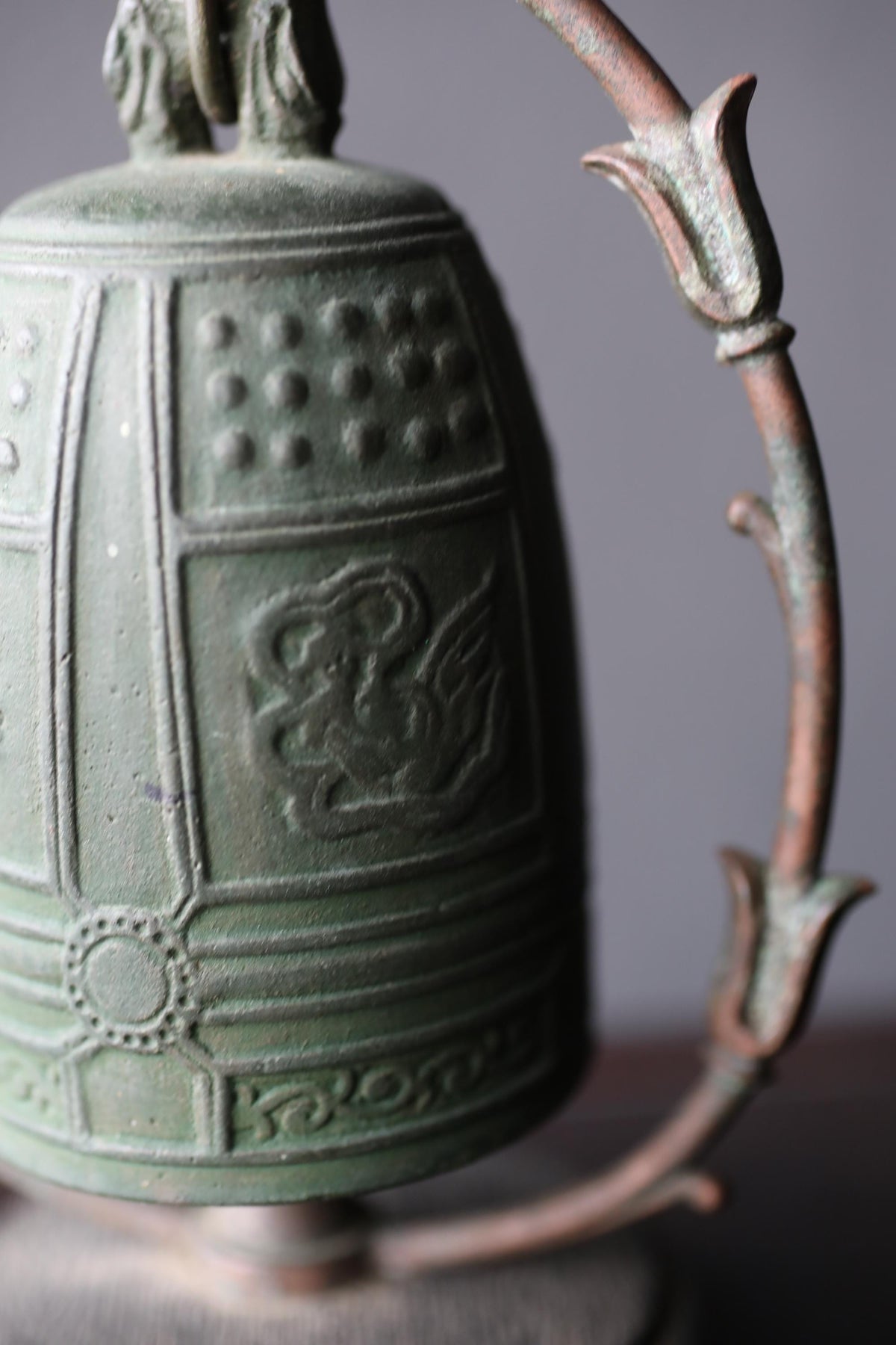 A close-up image of a green metal bell with a decorative design on its surface.