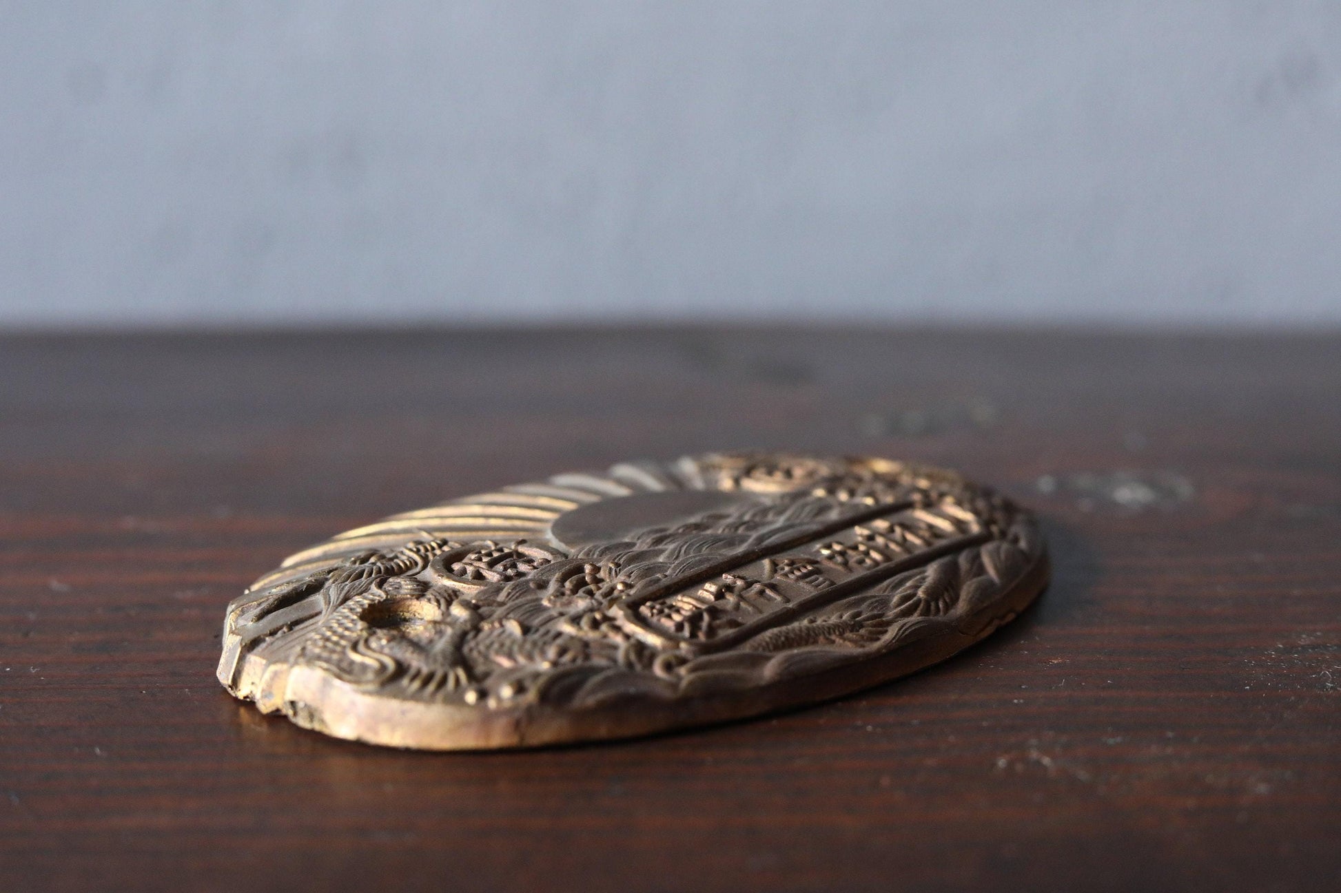 a close-up view of a decorative metal object, possibly a badge or plaque, resting on a wooden surface.