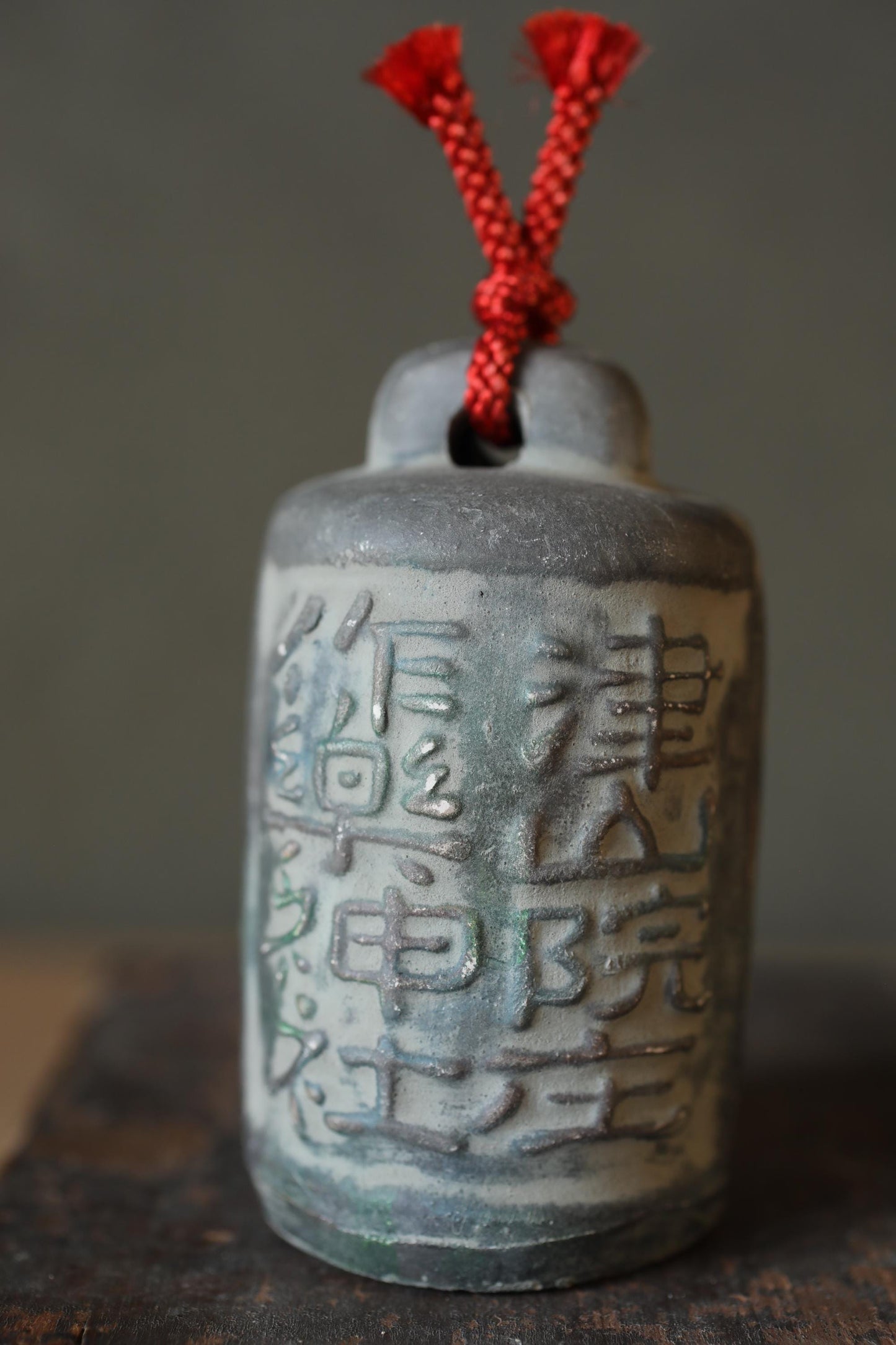 a gray ceramic object with red strings attached to it, which appears to be a decorative piece.