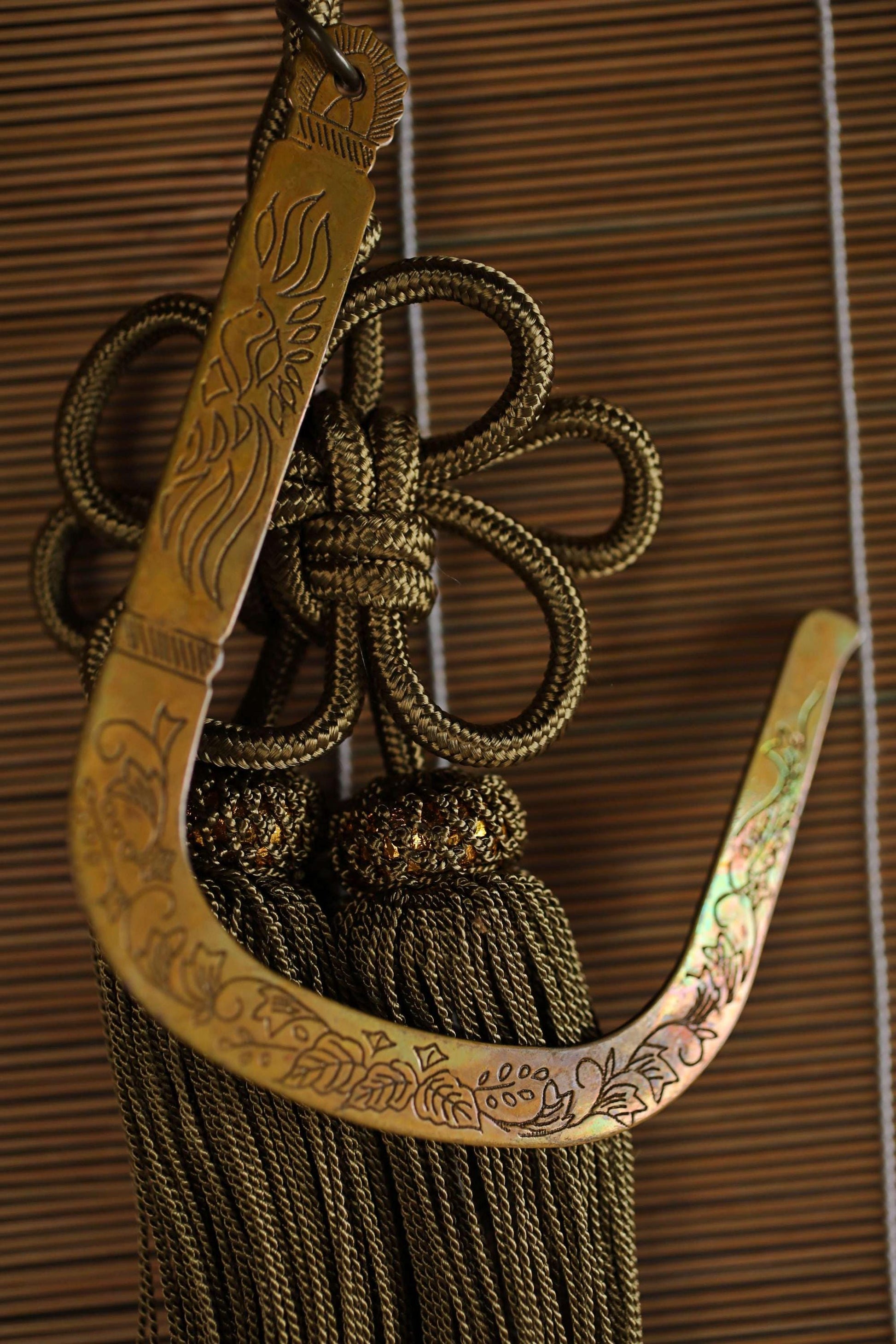 a decorative tassel with a floral design, hanging on a wooden surface.