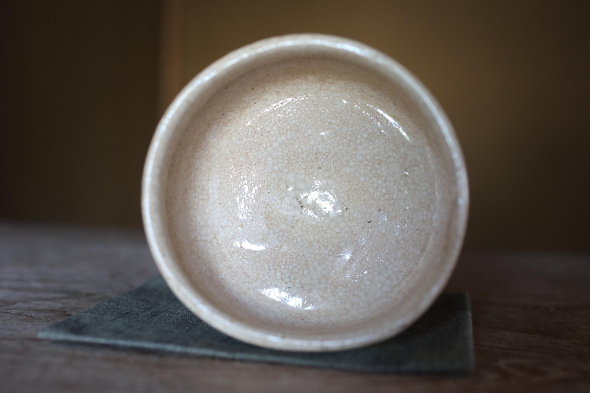 A white ceramic bowl with a speckled texture sits on a dark surface, possibly a piece of cloth or a coaster.