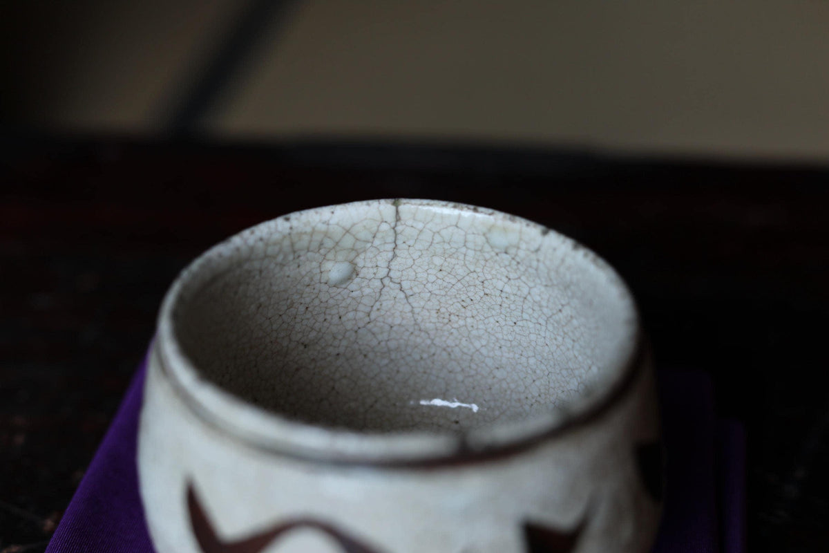 A close-up view of a white ceramic bowl with a cracked and textured surface, placed on a dark surface.
