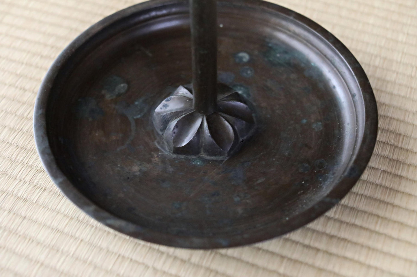 a close-up view of a dark metal object, possibly a candle holder or a decorative piece, placed on a woven mat.