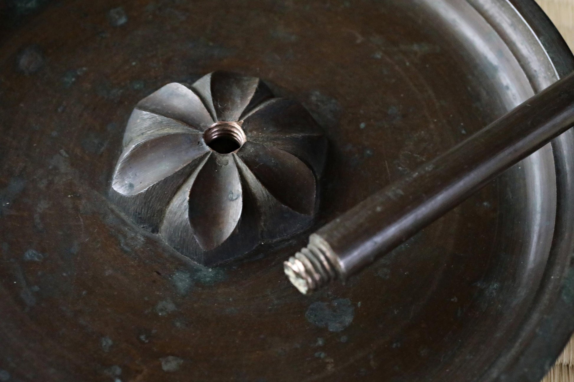 A close-up view of a metal object with a hole in the center, resting on a dark surface.