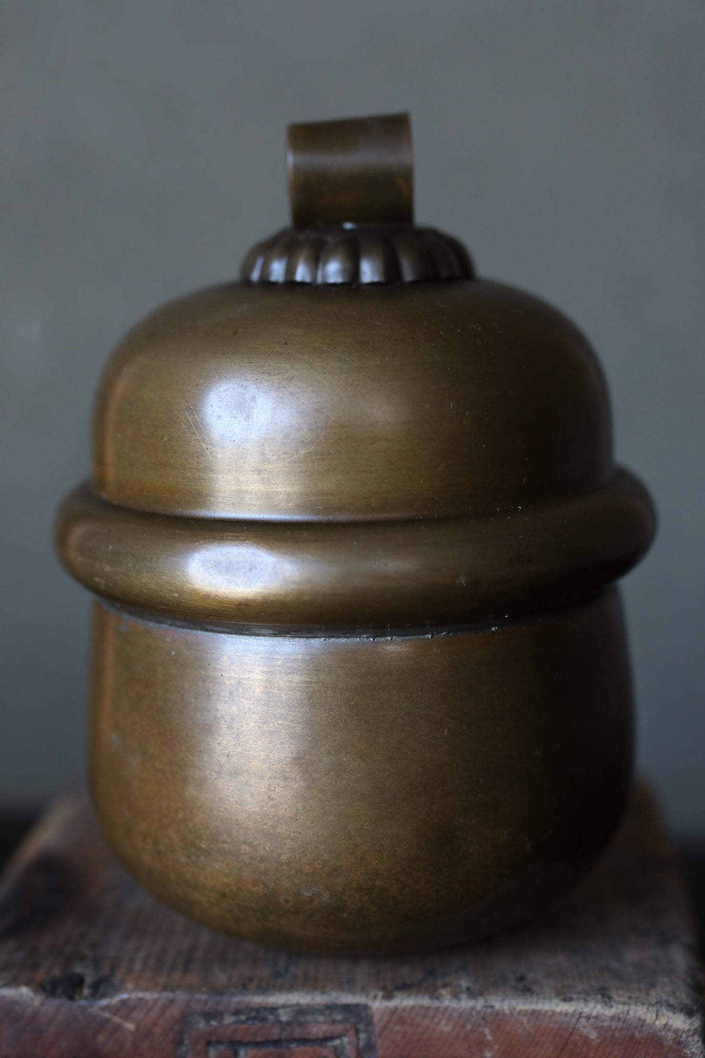 A shiny, brass-colored metal container with a lid, sitting on a wooden surface.