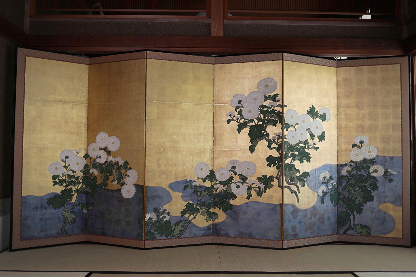 A large, multi-panel screen with a floral design featuring white flowers and green leaves.
