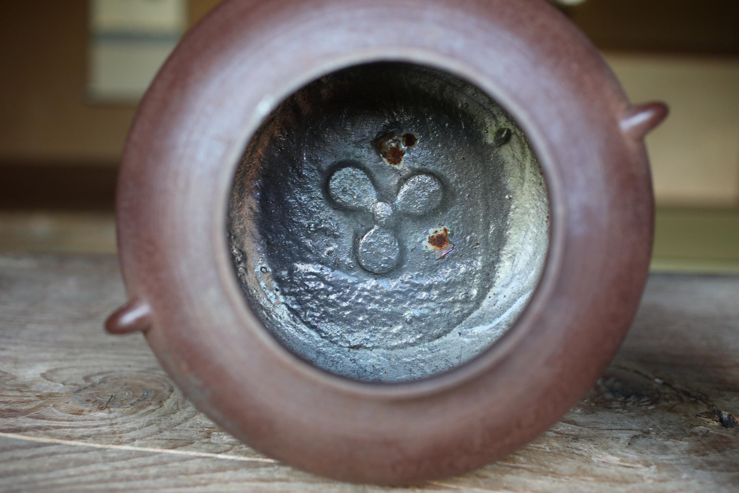 the inside of a brown ceramic container, possibly a teapot or vase, with a metal pattern visible inside.